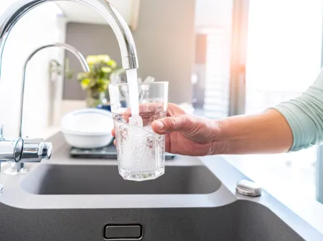 Eine Person füllt ein Glas am Wasserhahn
