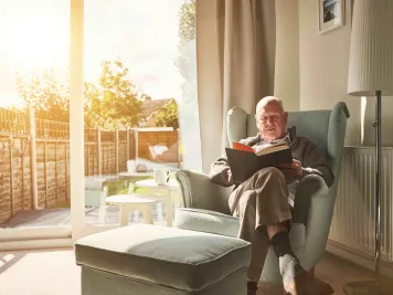 Ein Mann liest ein Buch und hat es gemütlich warm Zuhause.