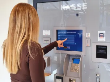 Eine junge Frau tippt auf den Bildschirm des Kassenautomaten im Kundencenter der Stadtwerke.