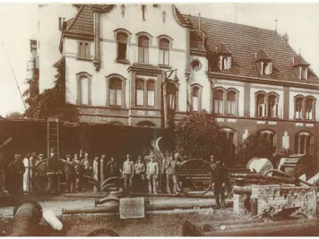 Schwarz-Weiß-Foto von 1924 mit den Arbeitern und Teilen der Fernwärmerohrleitungen vor dem Städtischen Elektrizitätswerk.