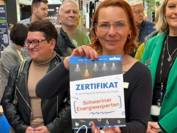 Eine Mitarbeiterin der Stadtwerke Schwerin hält ein Zertifikat in den Händen.
