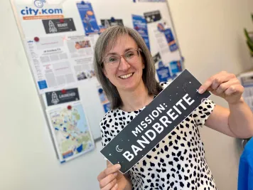 Frau im Büro mit Schild "Mission Bandbreite"