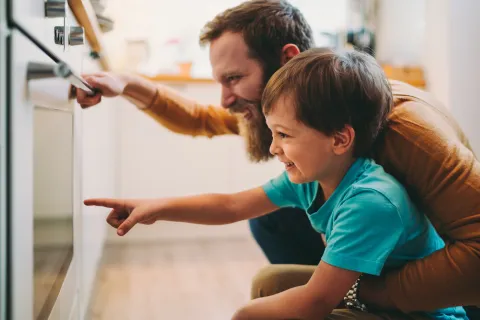 Vater und Sohn schauen begeistert in einen Backofen.