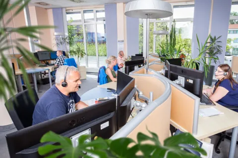 Blick in den Telefonservice-Raum der SWS: Mehrere Mitarbeitende telefonieren mit Headsets