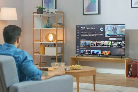 Ein Mann sitzt auf dem Sofa und streamt online Fernsehen IPTV.