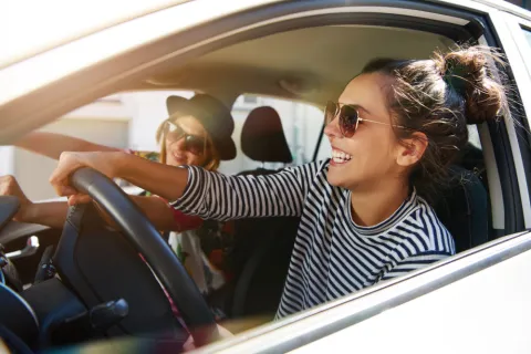 Zwei junge Frauen fahren im Auto und haben Spaß.