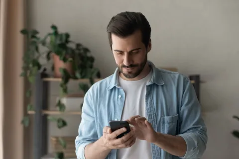Mann tippt zuhause auf dem Smartphone