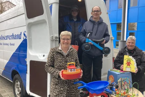 Vor einem Transporter vom Arbeitslosenverband Schwerin präsentieren Frauen und Männer gespendete Spielsachen.