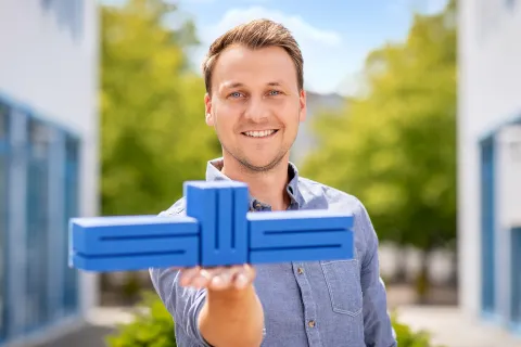 Ein Mann hält das Stadtwerke-Logo auf der Hand und lächelt in die Kamera.