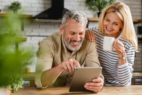 Pärchen steht in der Küche und schaut sich etwas auf dem Tablet an