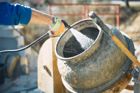 Bauarbeiter füllt Wasser in einen Betonmischer