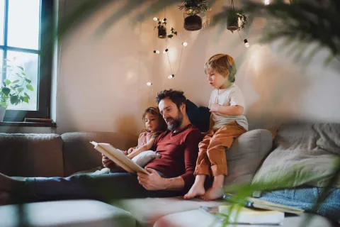 Mann liest Kindern unter einer Lichterkette vor.