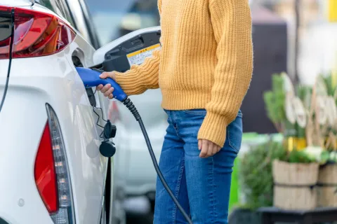 Eine Frau schließt ihr Elektroauto an eine Ladestation an.