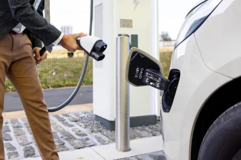 Mann schließt Elektroauto an eine öffentliche Ladesäule an.