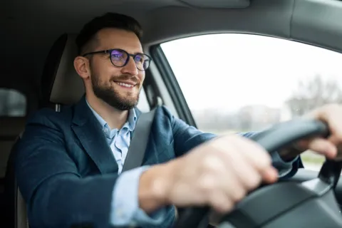 Ein Mann fährt fröhlich sein Auto.