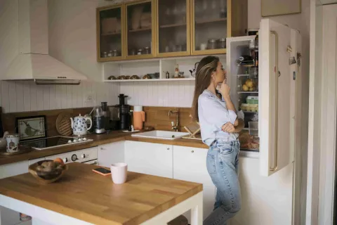 Frau schaut in ihren Kühlschrank.