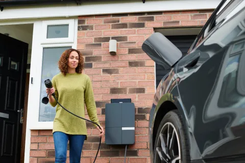 Frau schließt ihr Elektroauto an die Wallbox an.