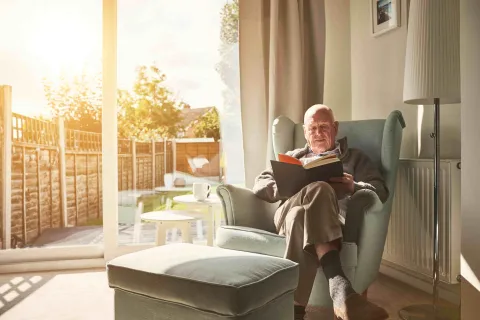 Mann liest ein Buch und hat es gemütlich warm Zuhause.