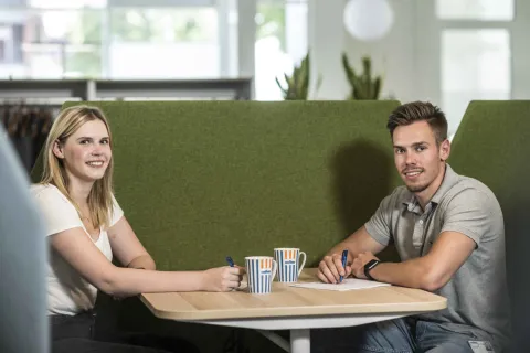 Zwei Azubis sitzen zusammen an einem Tisch.