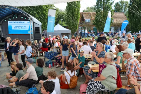 Eine Menschenmenge sitzt auf Bänken um die Stadtwerke-Bühne auf dem Insel- und Strandfest.