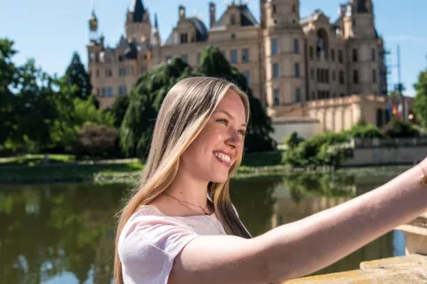 Eine Frau nimmt ein Selfie vor dem Schweriner Schloss von sich auf.