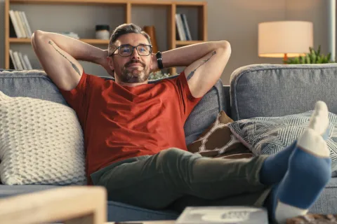 Ein Mann lehnt sich entspannt auf dem Sofa zurück.