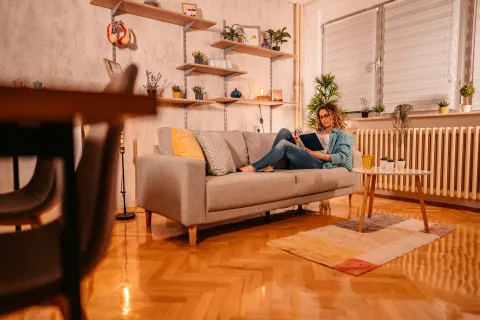 Eine Frau sitzt Zuhause auf ihrem Sofa.