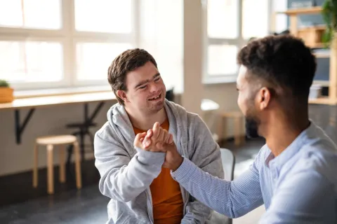 Mann mit Down-Syndrom spricht mit Betreuer.