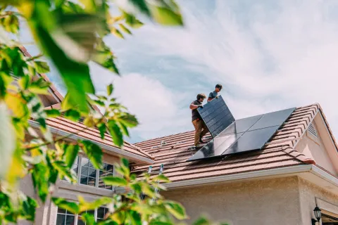 Zwei Männer installieren Solarmodule auf einem Dach.