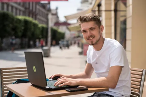 Ein Mann sitzt vor seinem Laptop im Café.