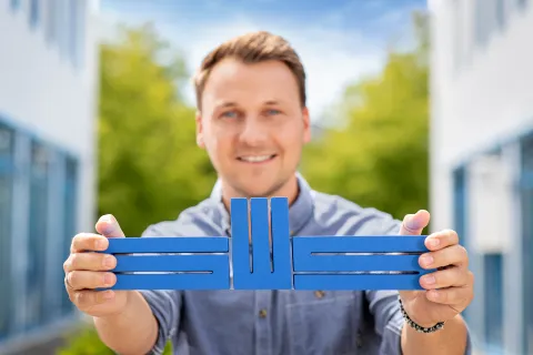 Ein junger Mann hält das Logo der Stadtwerke Schwerin mit beiden Händen in die Kamera.