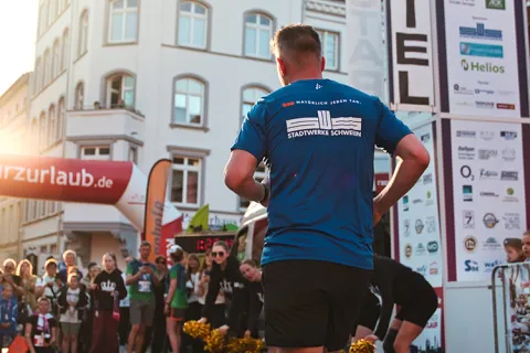 Zieleinlauf vom Schweriner Nachtlauf, ein Stadtwerke-Läufer ist von hinten zu sehen.