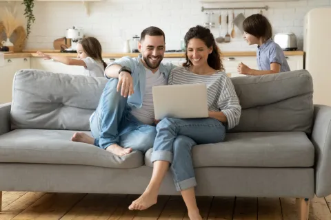 Eltern ruhen auf dem Sofa mit einem Laptop.