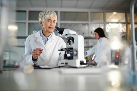 Eine Wissenschaftlerin nutzt ein Mikroskop.