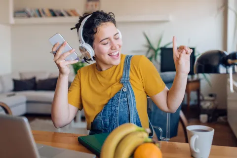 Junge Frau mit Kopfhörern hört Musik von ihrem Handy
