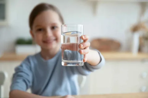 Kind freut sich über ein Glas Wasser.