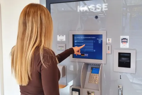 Eine junge Frau tippt auf den Bildschirm des Kassenautomaten im Kundencenter der Stadtwerke.