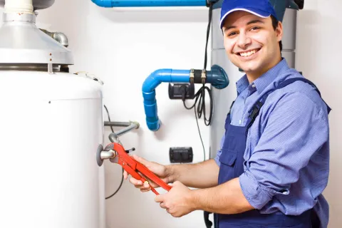 Ein junger Handwerker arbeitet am Warmwasserspeicher.