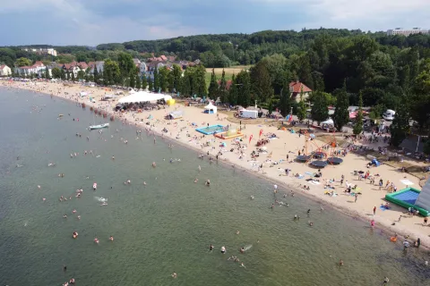 Luftaufnahme vom Zippendorfer Strand mit Festzelt und Kinderattraktionen. Zahlreiche Gäste am Strand und im See beim Baden.