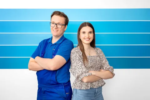 Ein junger Mann und eine junge Frau stehen Rücken an Rücken.
