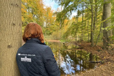 Eine Stadtwerkemitarbeiterin lehnt sich an einen Baum.