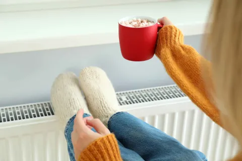 Eine Frau legt Ihre Füße an die warme Heizung.