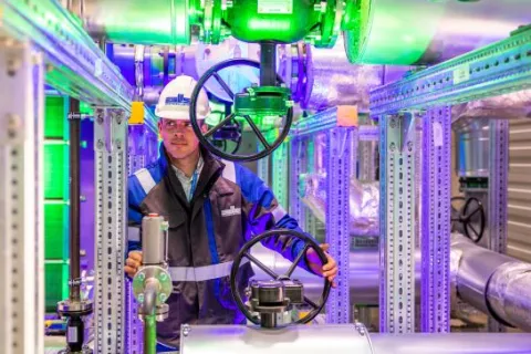 Stadtwerkemitarbeiter im Wärmepumpenraum einer Geothermie-Anlage.