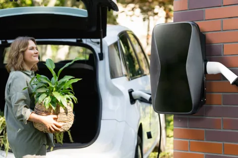 Eine Frau lädt ihr E-Auto an einer Wallbox.