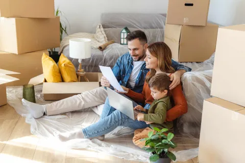 Eine Familie sitzt vor gepackten Kartons, bereit für den Umzug.