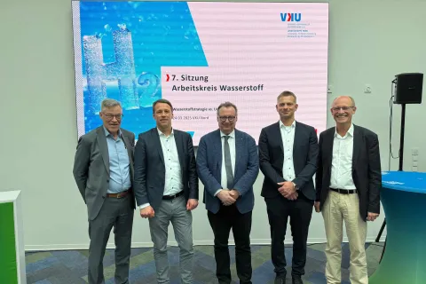 Vertreter aus Politik und Wirtschaft in MV stehen vor dem Screen zur 7. Sitzung des Arbeitskreises Wasserstoff.