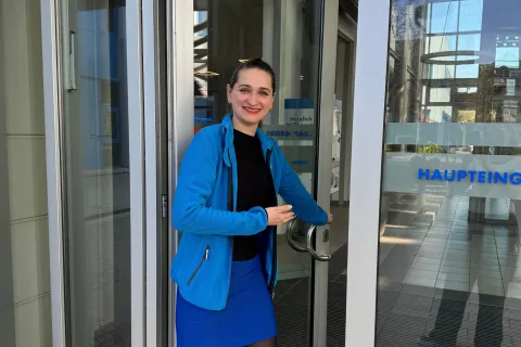 Eine Frau mit Stadtwerkekleidung öffnet die Tür zum Hauptstandort.