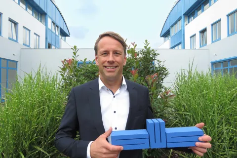Hanno Nispel hält das Stadtwerke-Logo in der Hand. Im Hintergrund ist der Innenhof des Stadtwerke-Standortes zu sehen.