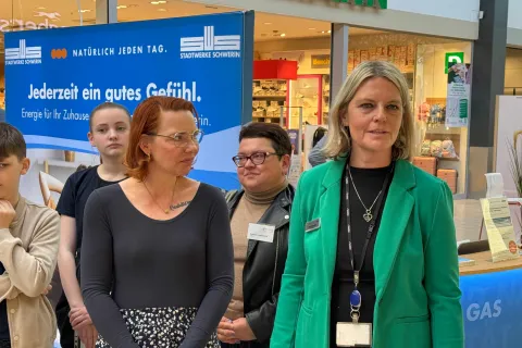 Zwei Frauen stehen vor dem Stand der Stadtwerke und begrüßen Gäste.