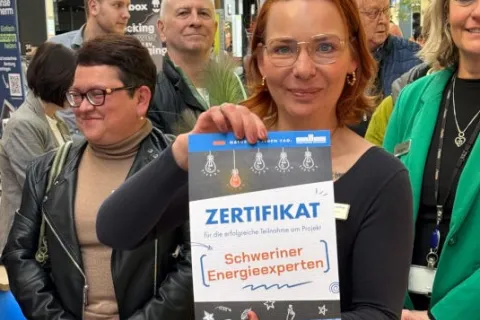 Mitarbeiterin der Stadtwerke Schwerin hält ein Zertifikat in den Händen.